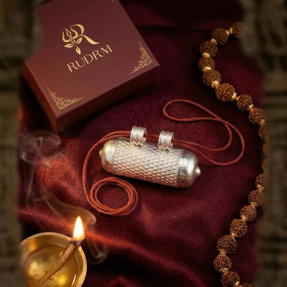 Silver Hanuman Gada pendant in a decorative box, with a rudraksha mala, incense smoke, and a lit diya on a maroon velvet background.