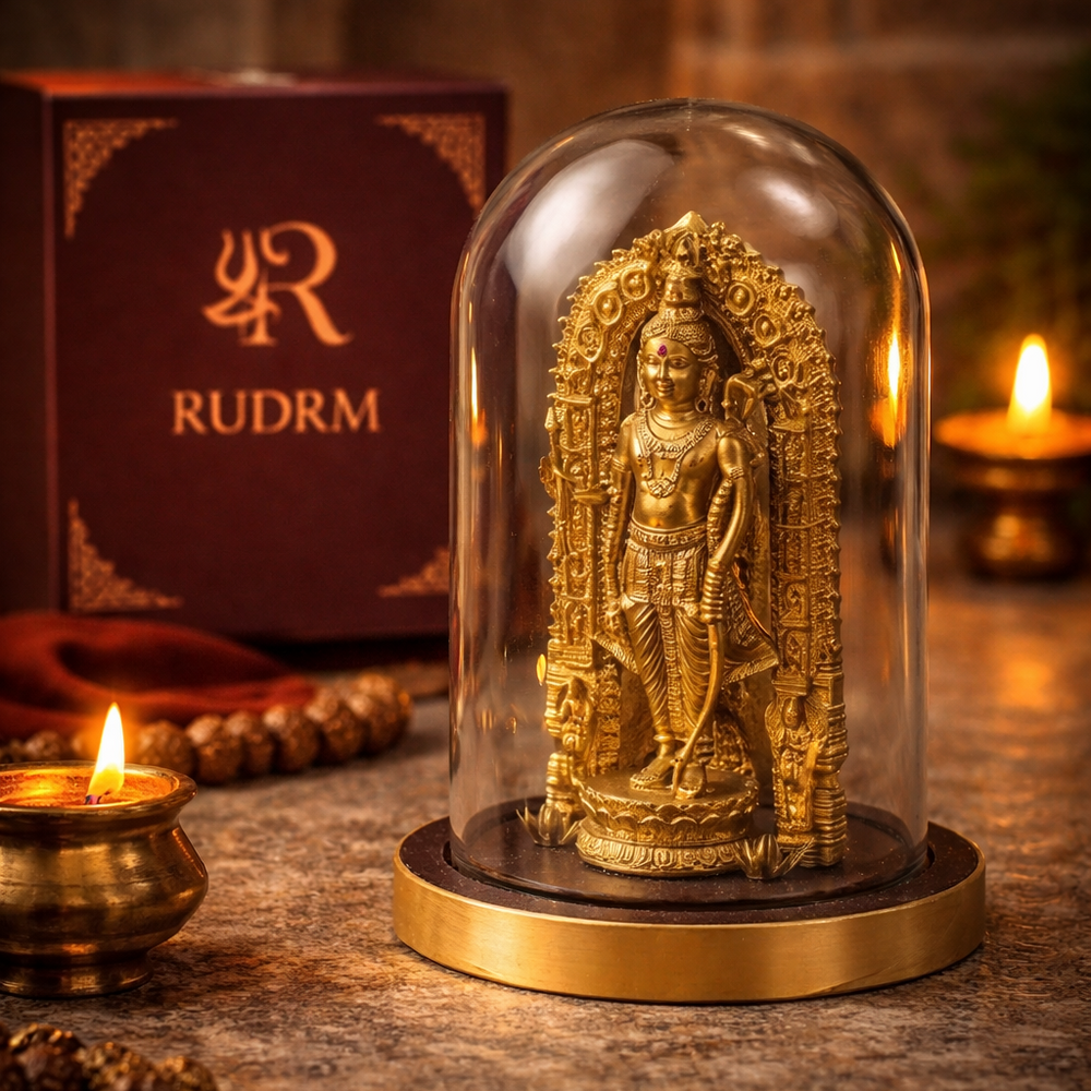 Golden statue of Lord Vishnu under a glass dome, placed next to a 'Rudrm' branded box, with a lit diya in the background.