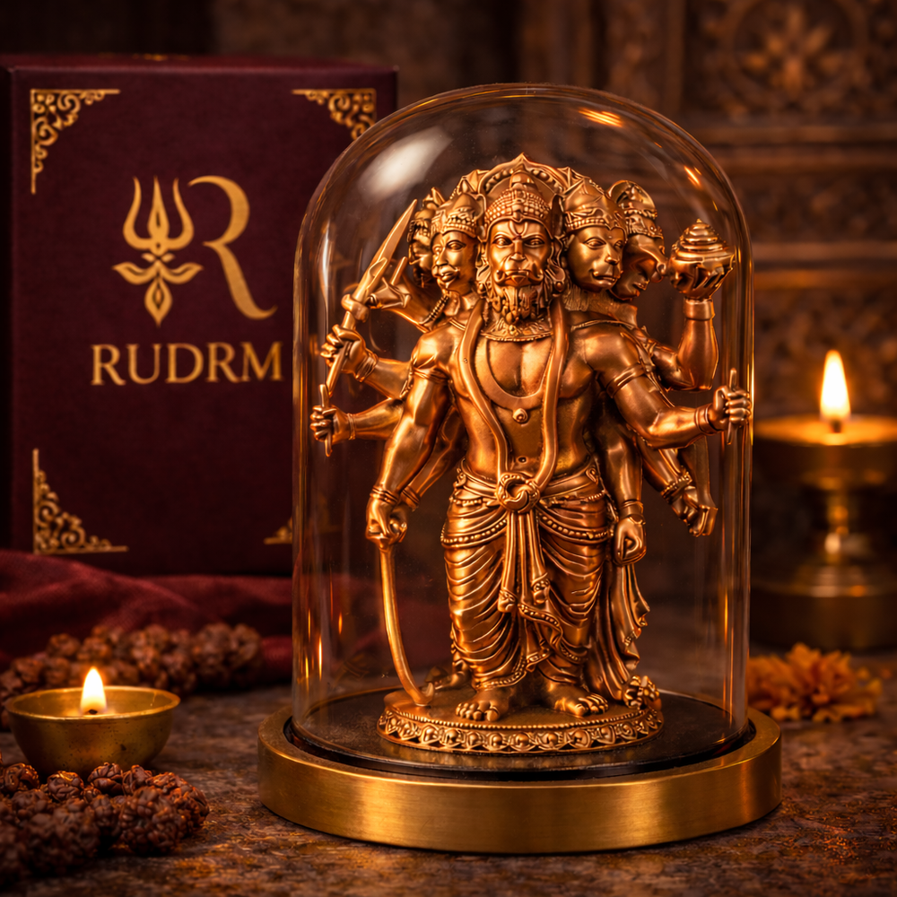 Bronze statue of Lord Hanuman with multiple heads and arms under a glass dome, placed next to a 'Rudrm' branded box, with a lit diya and rudraksha beads in the background.