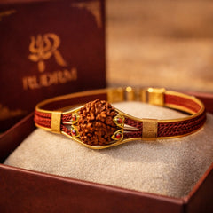 Rudraksha bracelet with a golden centerpiece, featuring colorful gemstone accents, placed inside a 'Rudrm' branded box on a soft beige cushion.
